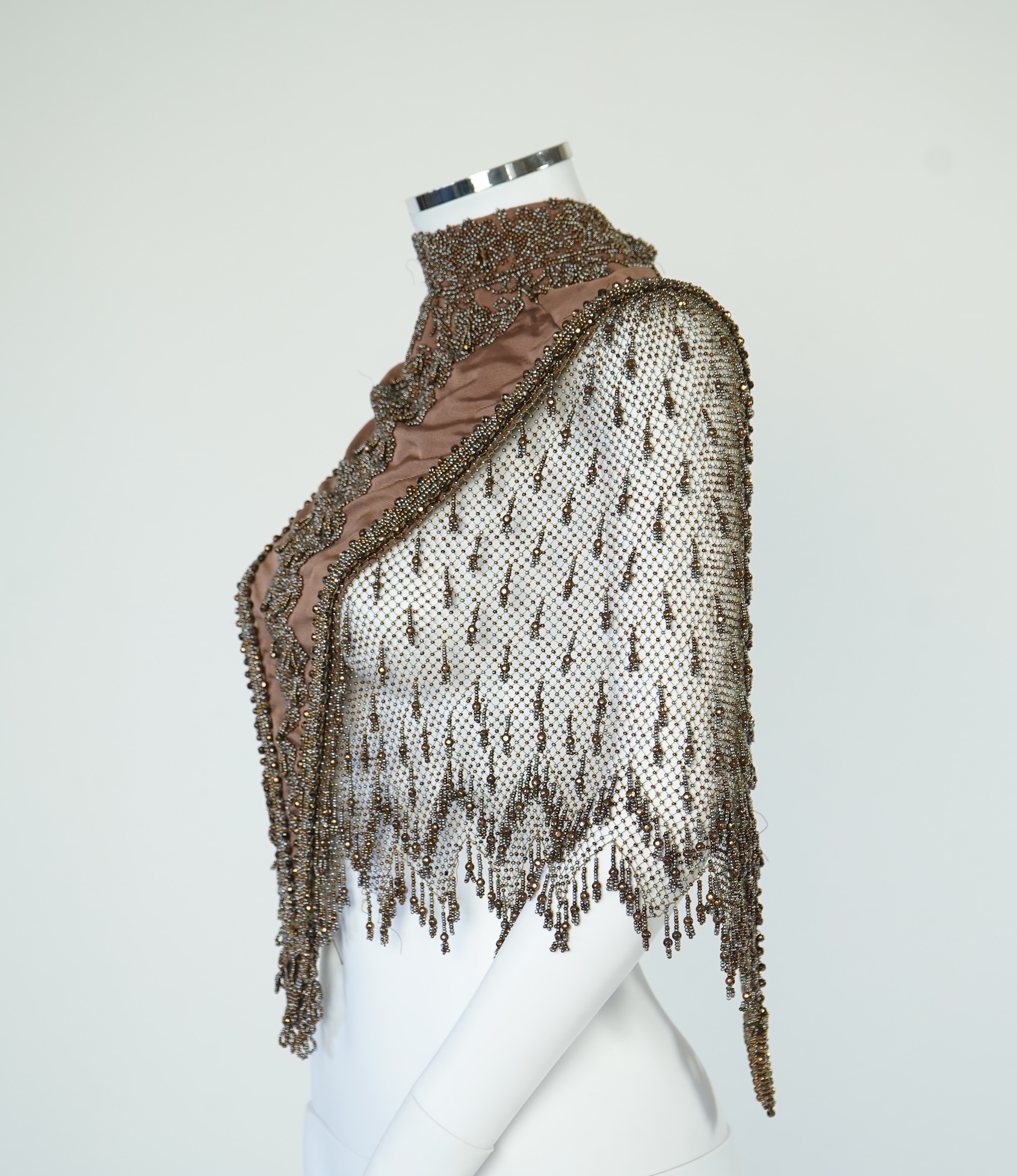 A late 19th century ladies ornate steel and brown beaded and fringed shoulder cape. Made as three ribbed silk panels with ornate beaded appliqués with a beaded and fringed net sleeved cape. Top of neck to bottom of beadi